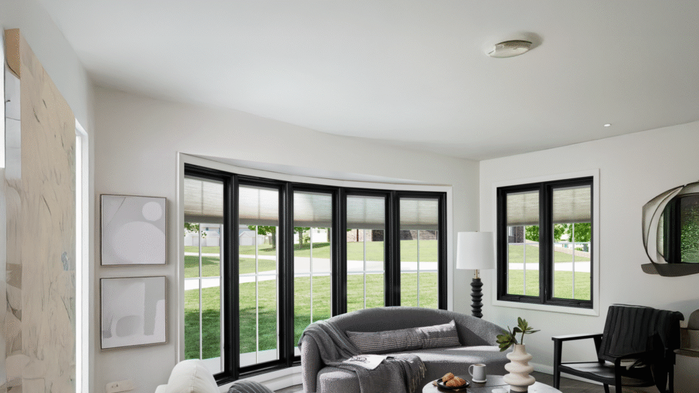Cozy living room with large black-framed bow windows bringing in natural light and warmth.