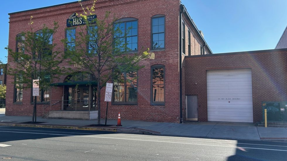 Welcoming brick building with large windows near a quiet street and green trees on a sunny day
