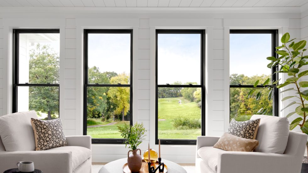 Bright living room with large windows framing a peaceful green landscape, inviting relaxation.