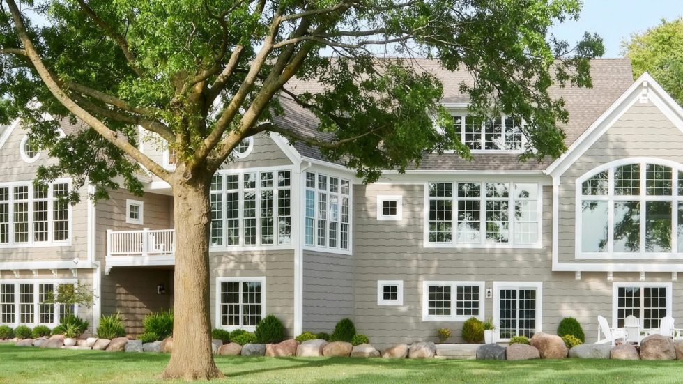 Spacious home with crisp white windows surrounded by lush greenery and inviting outdoor seating.
