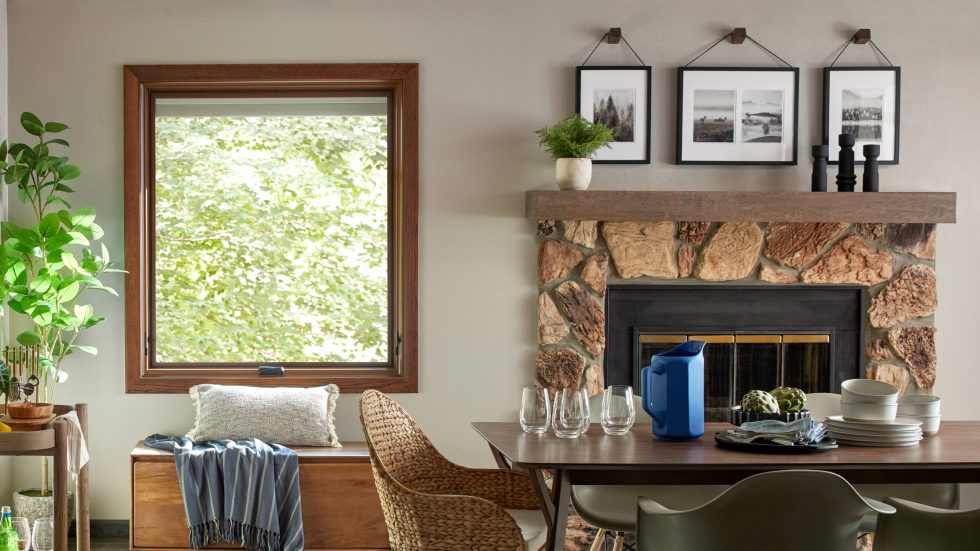 Cozy dining area with a wood-framed window, stone fireplace, and inviting decor.
