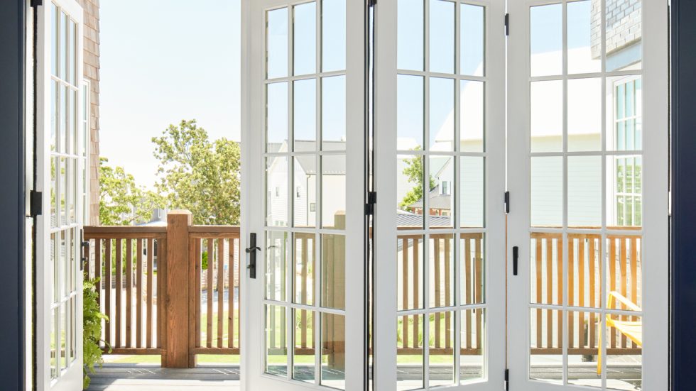 Bright bifold doors open to a sunny deck with a warm, welcoming neighborhood view.