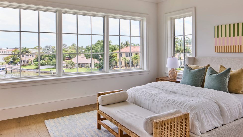 Bright bedroom with large casement windows showcasing a serene waterfront neighborhood view.