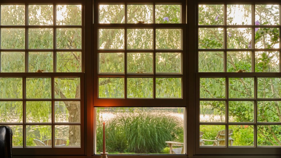Cozy view through double-hung windows framing a peaceful garden with seating for gathering.