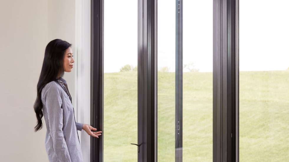 Woman enjoying natural light through sleek, durable fiberglass window in a peaceful home setting