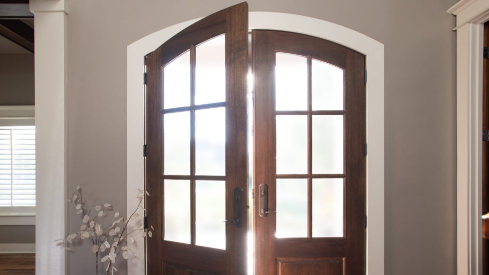 Warm wood French doors welcoming natural light into a cozy, inviting home entryway.