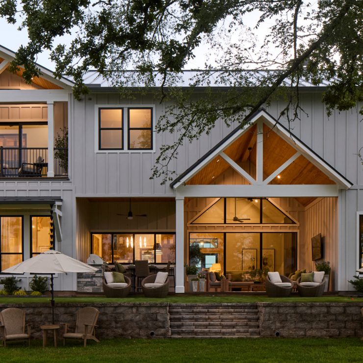 Warm-lit modern farmhouse with outdoor seating, promoting comfort and community connection.