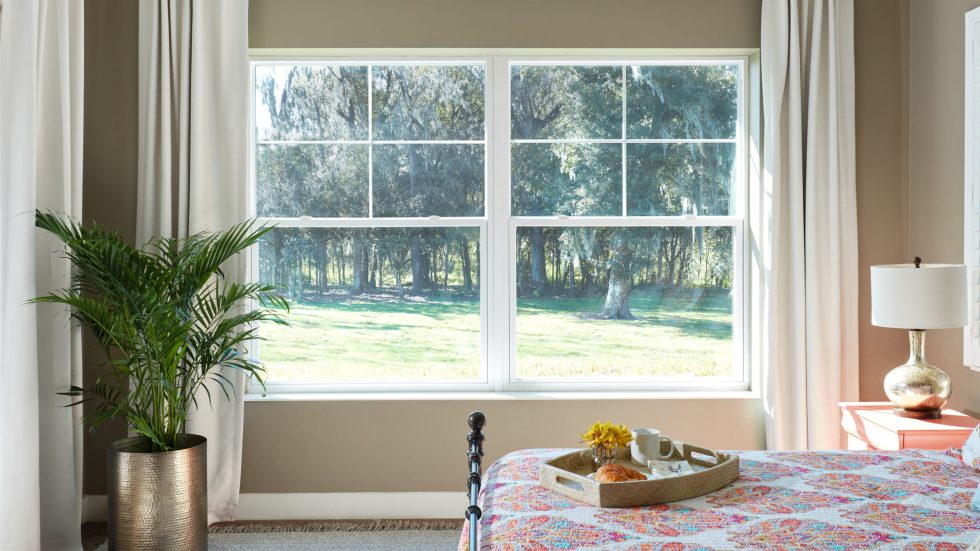 Bright bedroom with a single-hung window showcasing a serene outdoor view and cozy accents