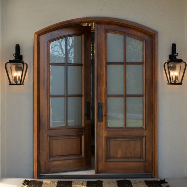 Inviting wood front doors with glass panels and classic lanterns, welcoming warmth at home entry.