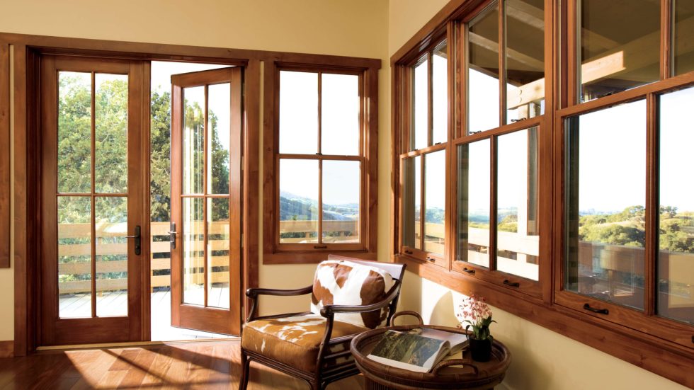 Sunlit room featuring warm wood windows and doors opening to a peaceful outdoor view.