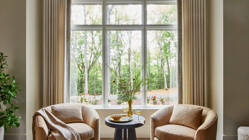 Cozy seating by large wood-framed window invites warm, natural light and connection.